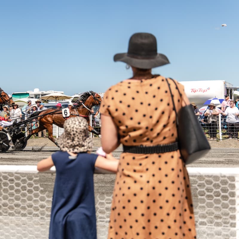 A well dressed lady and her young daughter enjoying the Harness races