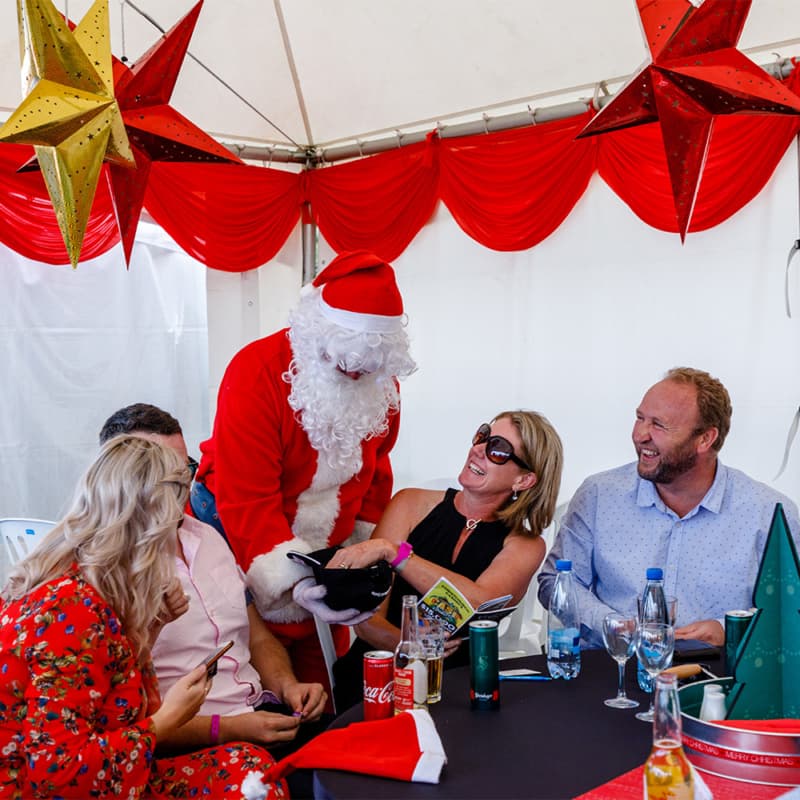 Santa Claus distributing gifts to the attendees at the Harness Life racing event